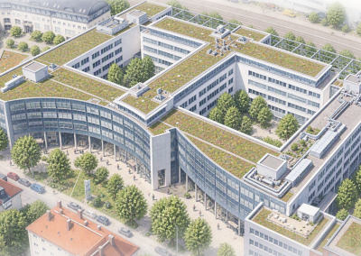 Senkrechte Luftaufnahme eines großflächigen, symmetrisch aufgebauten Büro- und Verwaltungsgebäudekomplexes in städtischer Umgebung. Das Gebäudeensemble verfügt über mehrere miteinander verbundene Baukörper mit begrünten Flachdächern und klar strukturierten Innenhöfen. Die Dachflächen zeigen technische Aufbauten sowie extensive Begrünung. Umgeben ist der Komplex von Baumreihen, Verkehrsflächen und angrenzender Bebauung. Die Aufnahme verdeutlicht die funktionale Architektur, die nachhaltige Dachgestaltung und die strukturierte Anordnung des gesamten Areals. Das Bild eignet sich besonders zur Darstellung von Verwaltungsstandorten, Unternehmenszentralen oder modernen Gewerbeimmobilien.