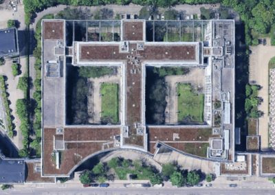 Senkrechte Luftaufnahme eines symmetrisch angeordneten Büro- und Verwaltungsgebäudekomplexes mit begrünten Innenhöfen und Flachdächern
