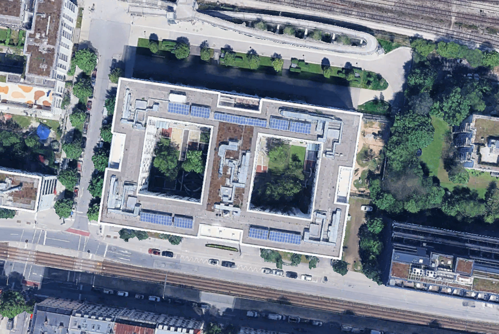 Luftaufnahme eines großen Bürokomplexes mit begrüntem Innenhof und Solaranlagen auf dem Dach