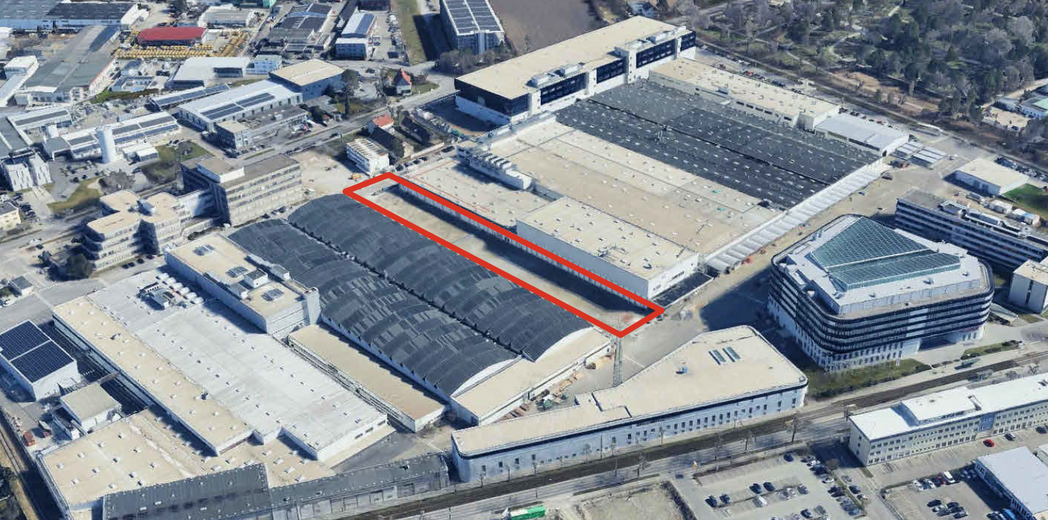 Aerialaufnahme eines Industrie- und Werksgeländes mit langgezogenem, rot markiertem Hallenbereich innerhalb eines großen Produktionskomplexes