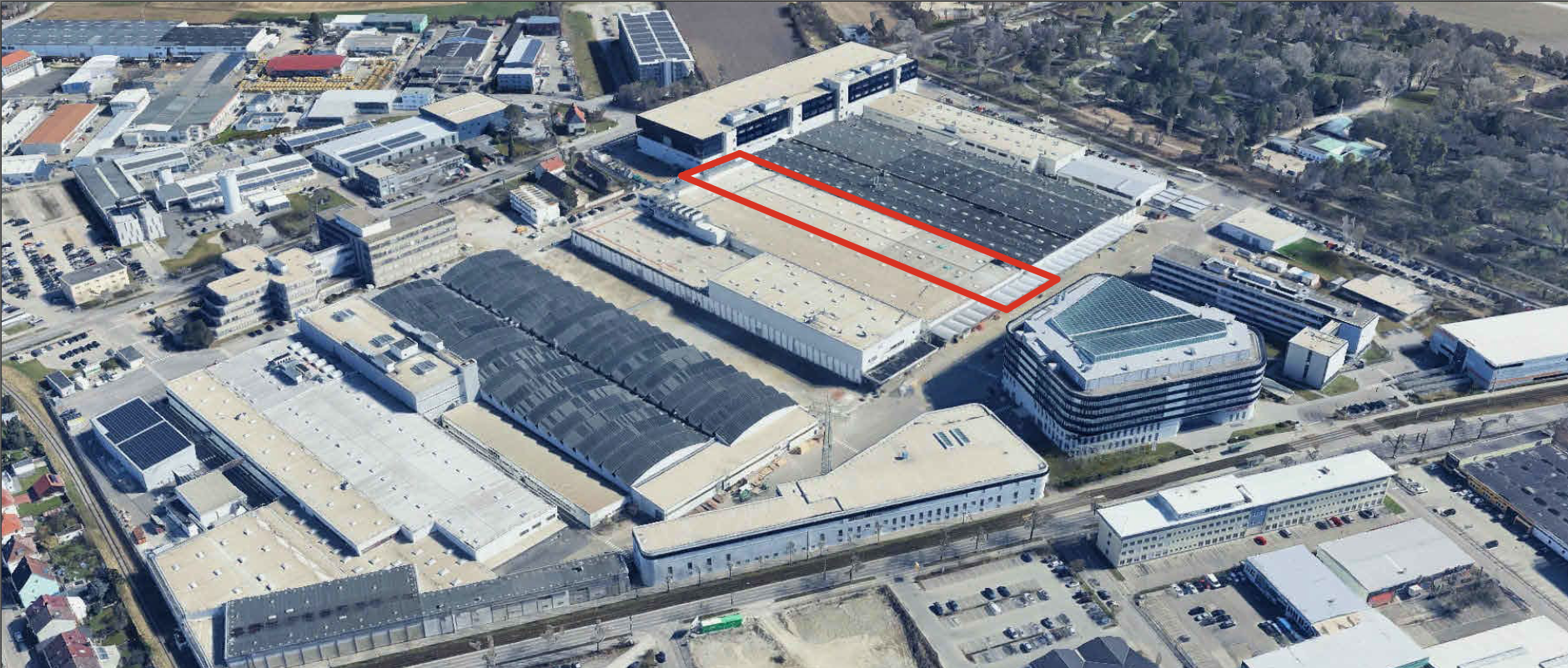 Aerialaufnahme eines Industrie- und Werksgeländes mit rechteckigem, rot markiertem Hallenbereich innerhalb eines großen Produktionskomplexes